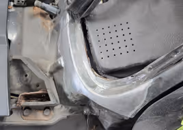 The same cowl area after cutting out the rust and welding in a new, custom-fabricated metal section, ground smooth and ready for finishing.