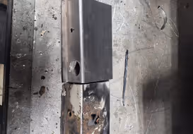 A side-by-side comparison of a rusted, original car part and its brand new, custom-fabricated replacement, showcasing metal shaping and replication skills.