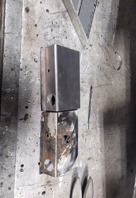 A rusted original part beside its custom-fabricated replacement, showing metal shaping and replication work.