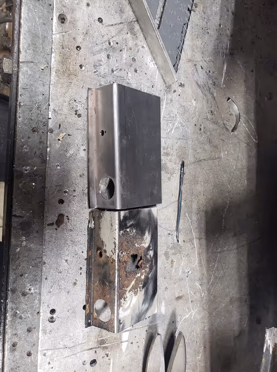 A side-by-side comparison of a rusted, original car part and its brand new, custom-fabricated replacement, showcasing metal shaping and replication skills.