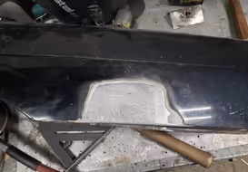A completed fender patch repair, with the new metal seamlessly welded in and ground smooth, blending perfectly with the original body lines.