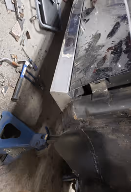 Fabrication and installation of a new, custom-made lower rocker panel section on a car supported by a jack stand.