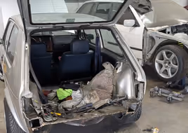 The rear of a silver Volkswagen Golf Mk1 with the bumper and lower panel removed, showing the extent of bodywork needed.