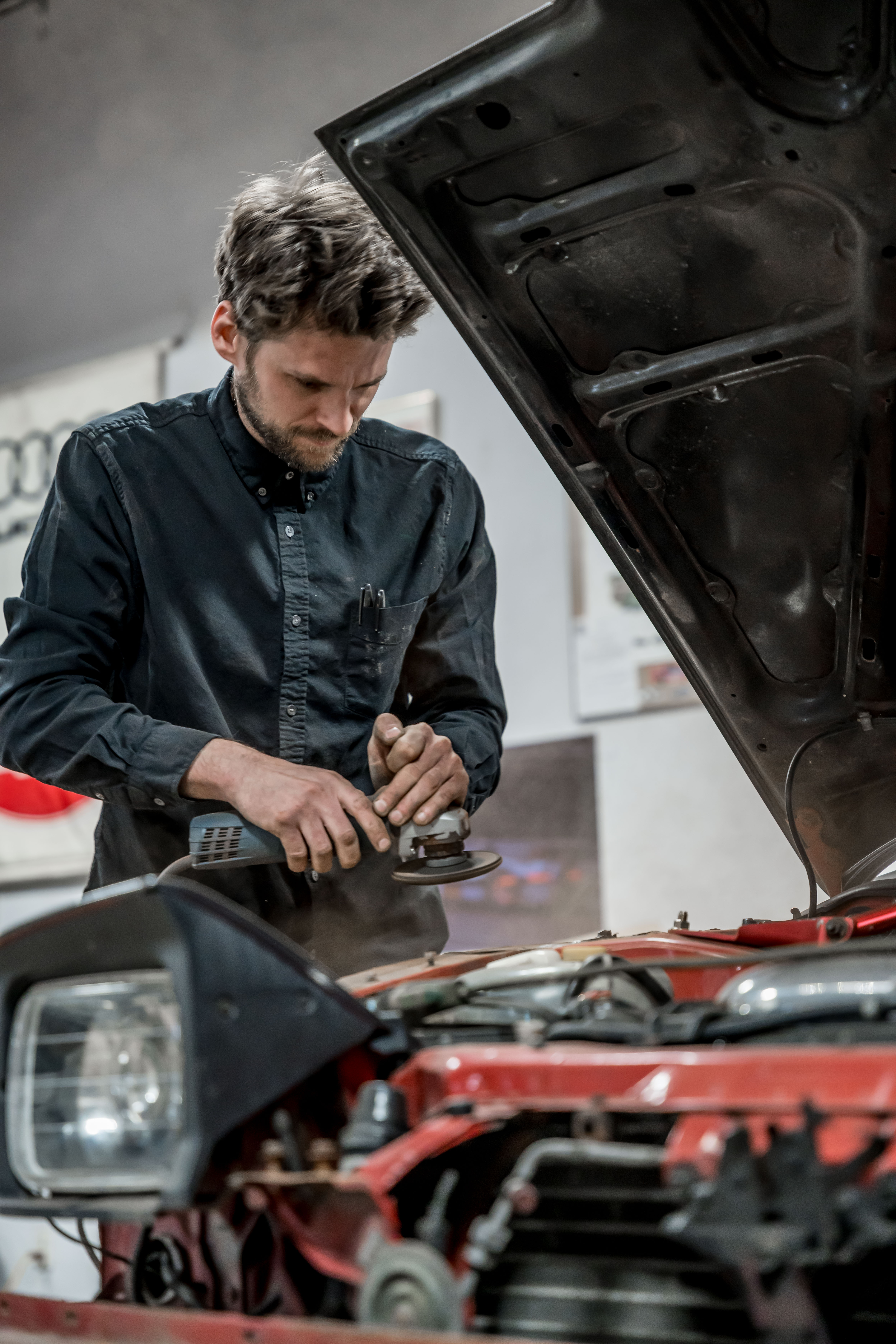 Dan standing at red car engine bay at DTM Fabrication