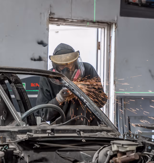 Mid-cut on a car body panel with sparks during fabrication.