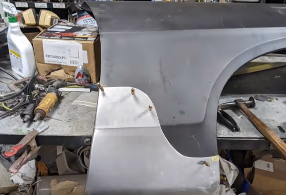 A custom fabricated metal patch panel, showing intricate bends and clean welds, resting on a workshop bench.
