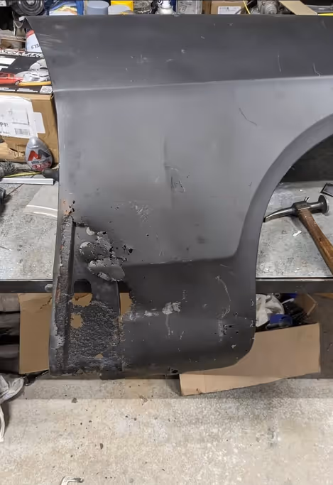 Rust damage on a vehicle panel before repair work begins.